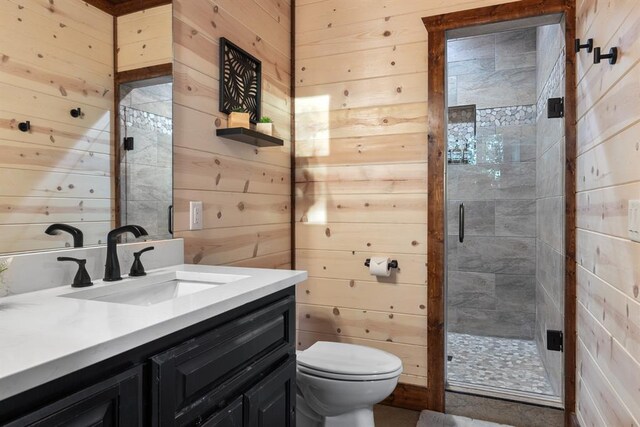 bathroom with toilet, vanity, wooden walls, and a shower with shower door