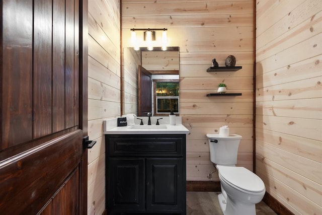 bathroom featuring vanity, toilet, and wood walls