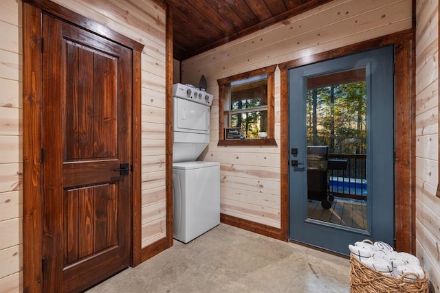 laundry room with wooden walls, wooden ceiling, and stacked washer / dryer