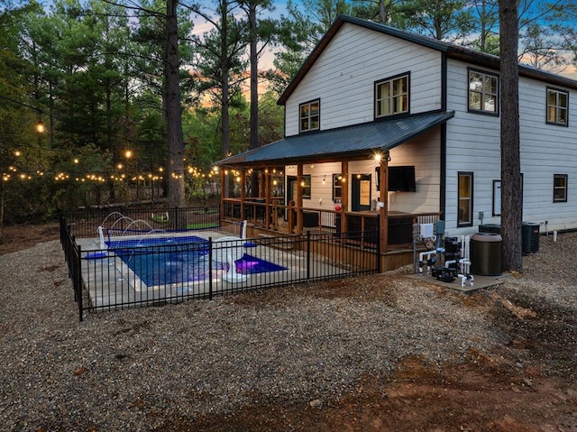 pool at dusk featuring a patio, pool water feature, and central AC