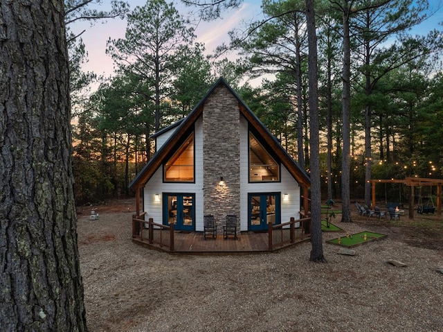 back house at dusk with french doors and a deck