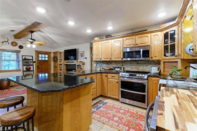 kitchen with a breakfast bar, ceiling fan, appliances with stainless steel finishes, tasteful backsplash, and kitchen peninsula