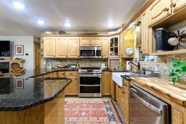 kitchen featuring kitchen peninsula, appliances with stainless steel finishes, decorative backsplash, dark stone counters, and light tile patterned floors