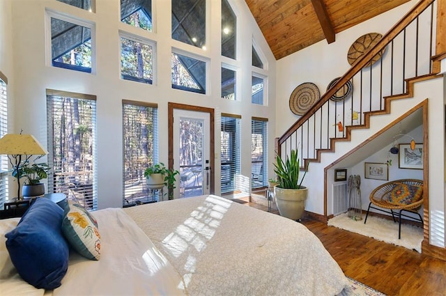 bedroom with hardwood / wood-style floors, beam ceiling, a towering ceiling, and wooden ceiling