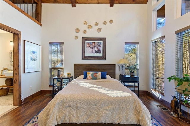 bedroom with beamed ceiling, a high ceiling, and dark hardwood / wood-style flooring