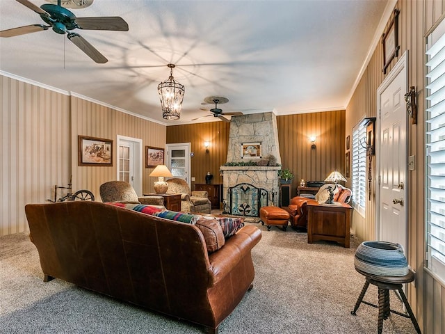 carpeted living room featuring ceiling fan with notable chandelier, a stone fireplace, and ornamental molding