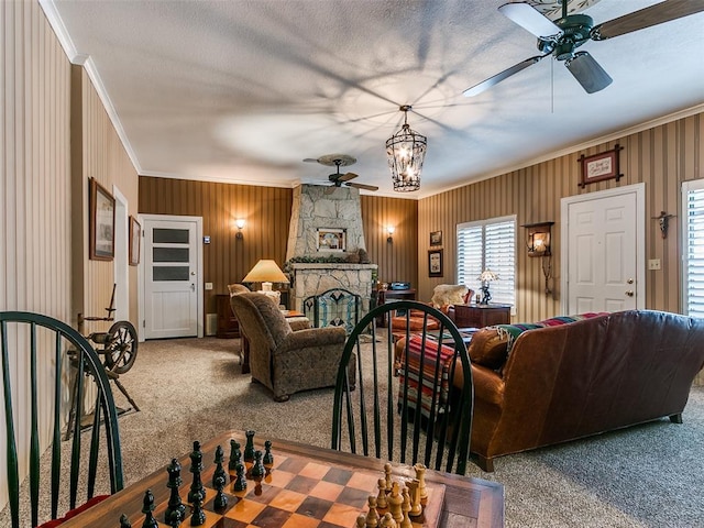 carpeted living room with a fireplace, ceiling fan with notable chandelier, and ornamental molding