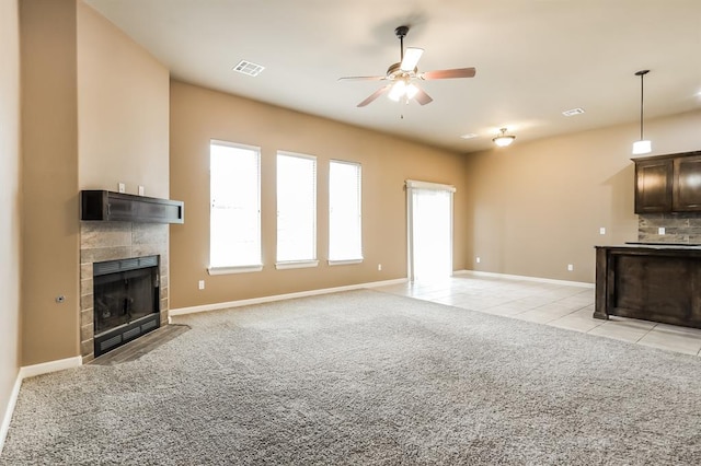 unfurnished living room with a fireplace, light colored carpet, and ceiling fan