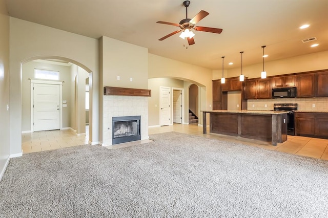 kitchen with electric range, light tile patterned flooring, pendant lighting, a fireplace, and a kitchen island