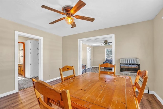 dining space featuring heating unit, ceiling fan, and wood-type flooring