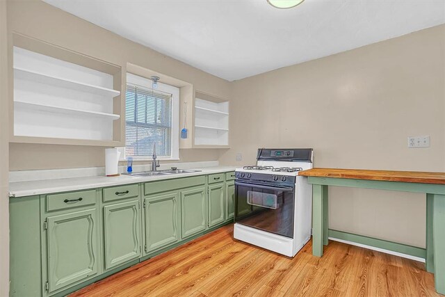 kitchen featuring light hardwood / wood-style floors, green cabinets, white range with gas stovetop, and sink