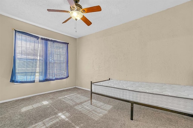 unfurnished bedroom with a textured ceiling, carpet floors, and ceiling fan