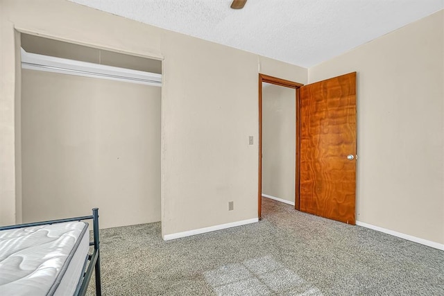 unfurnished bedroom featuring a textured ceiling, carpet floors, a closet, and ceiling fan