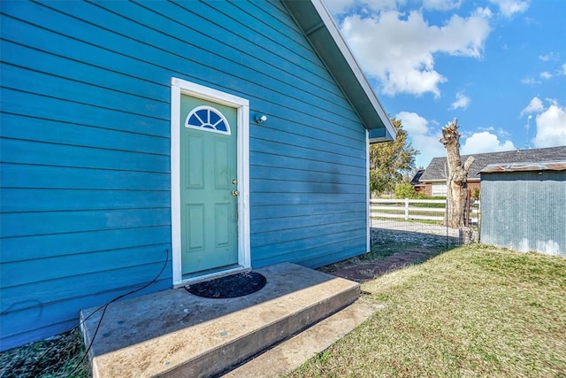 view of exterior entry featuring a lawn