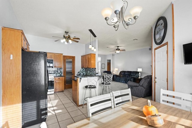 tiled dining space featuring ceiling fan with notable chandelier