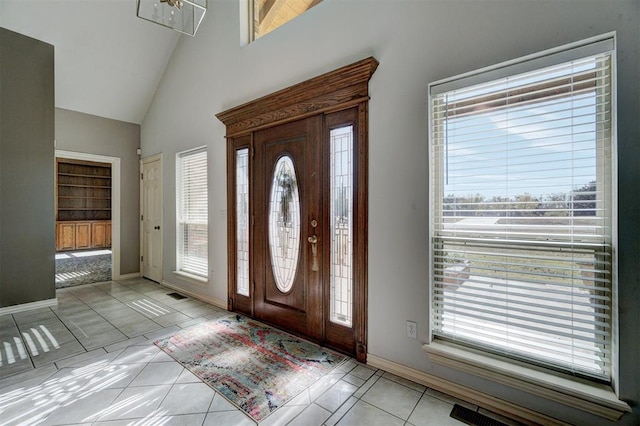 tiled foyer with high vaulted ceiling and a chandelier