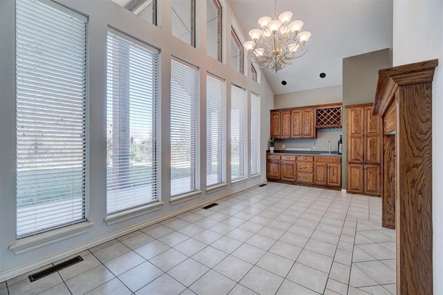 kitchen featuring sink, light tile patterned floors, decorative light fixtures, an inviting chandelier, and high vaulted ceiling