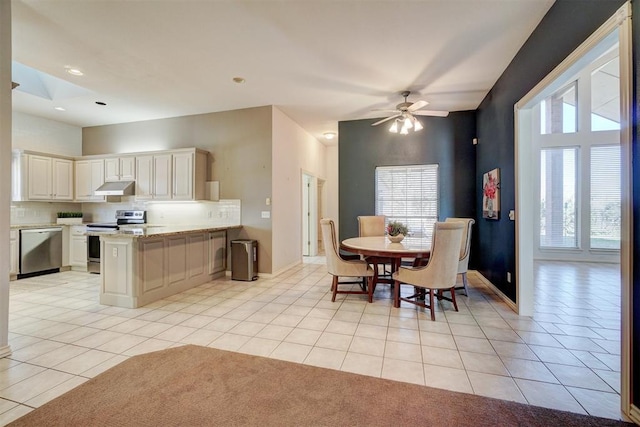 kitchen with kitchen peninsula, a wealth of natural light, light tile patterned flooring, and stainless steel appliances