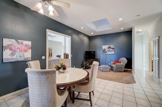 tiled dining space featuring a skylight and ceiling fan