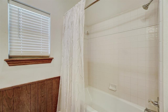 bathroom featuring wood walls and shower / bathtub combination with curtain