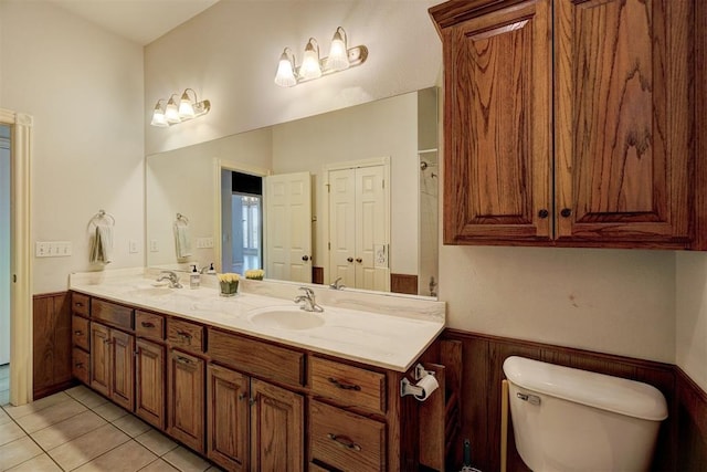 bathroom with toilet, vanity, tile patterned floors, and wooden walls