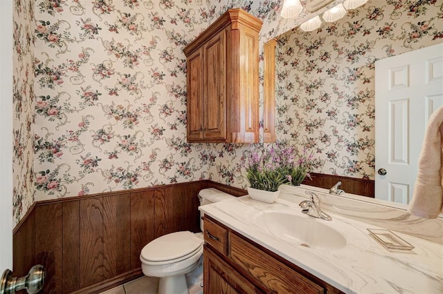 bathroom with vanity, wood walls, and toilet