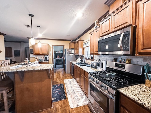 kitchen with light stone counters, stainless steel appliances, sink, wood-type flooring, and a center island with sink