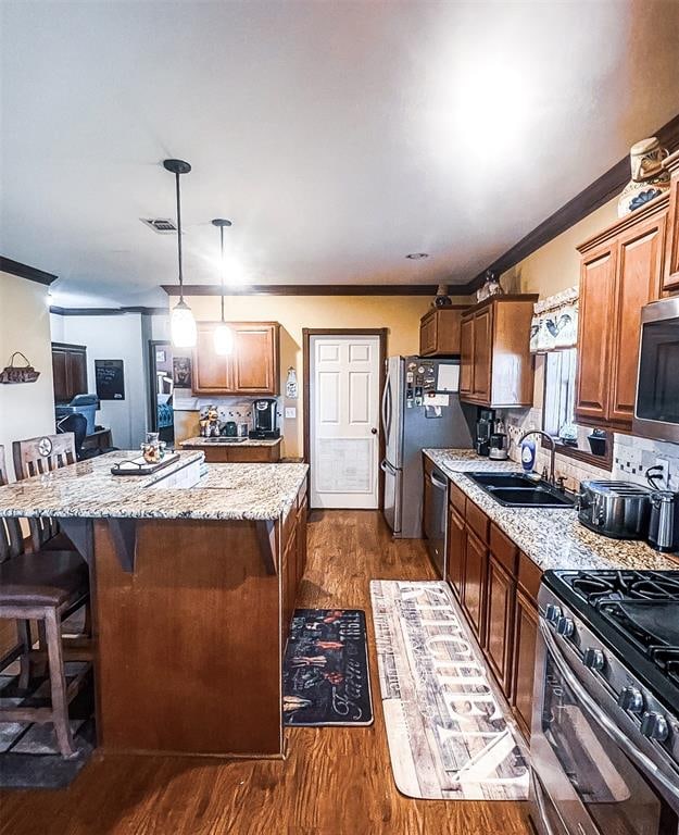 kitchen featuring tasteful backsplash, stainless steel appliances, dark wood-type flooring, sink, and pendant lighting