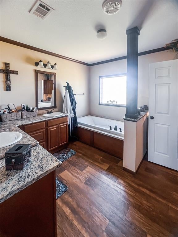 bathroom with vanity, hardwood / wood-style flooring, crown molding, and a tub