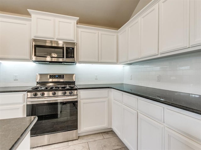2213 Waterbrook Ct, Norman, OK 73026 - kitchen with appliances with stainless steel finishes, decorative backsplash, white cabinetry, light tile patterned flooring, and vaulted ceiling