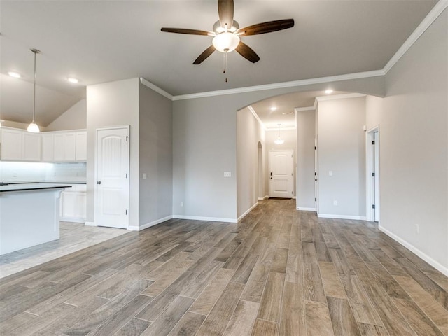 2213 Waterbrook Ct, Norman, OK 73026 - unfurnished living room featuring arched walkways, a ceiling fan, light wood-type flooring, crown molding, and baseboards
