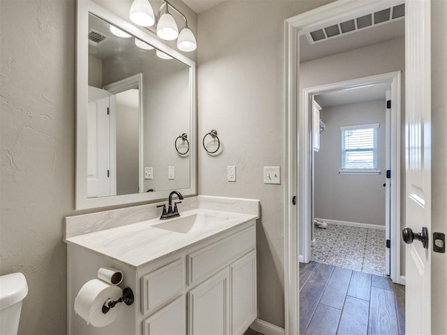2213 Waterbrook Ct, Norman, OK 73026 - bathroom featuring vanity, toilet, wood finished floors, and baseboards