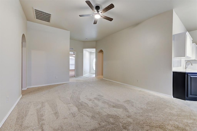 unfurnished living room featuring light colored carpet, ceiling fan, and sink