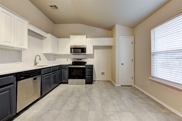 kitchen with white cabinetry, sink, stainless steel appliances, tasteful backsplash, and lofted ceiling