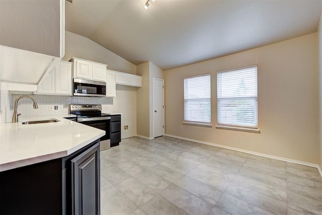 kitchen featuring lofted ceiling, backsplash, sink, appliances with stainless steel finishes, and white cabinetry