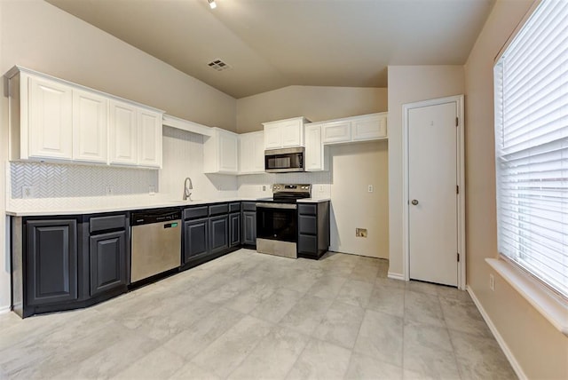 kitchen with white cabinets, a wealth of natural light, appliances with stainless steel finishes, and vaulted ceiling