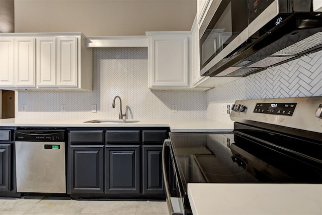 kitchen with appliances with stainless steel finishes, backsplash, sink, light tile patterned floors, and white cabinets