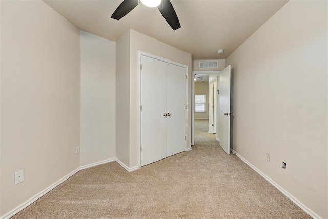 unfurnished bedroom featuring ceiling fan, light colored carpet, and a closet