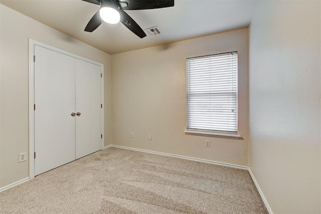 unfurnished bedroom featuring light carpet, a closet, and ceiling fan