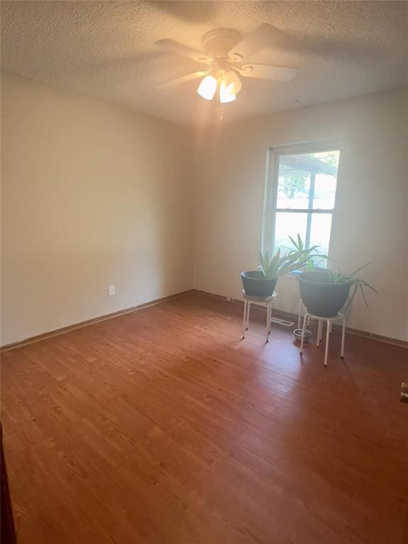 empty room featuring ceiling fan, wood-type flooring, and a textured ceiling