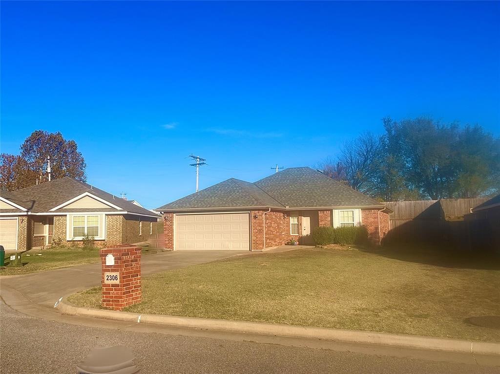 ranch-style house with a garage and a front lawn