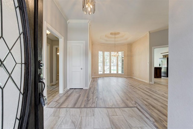 entryway featuring light hardwood / wood-style floors, crown molding, and a notable chandelier