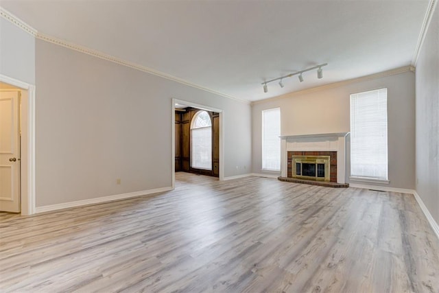 unfurnished living room featuring a fireplace, track lighting, light hardwood / wood-style flooring, and ornamental molding