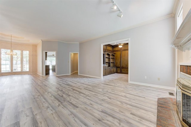 unfurnished living room with ceiling fan with notable chandelier, light hardwood / wood-style floors, crown molding, and track lighting