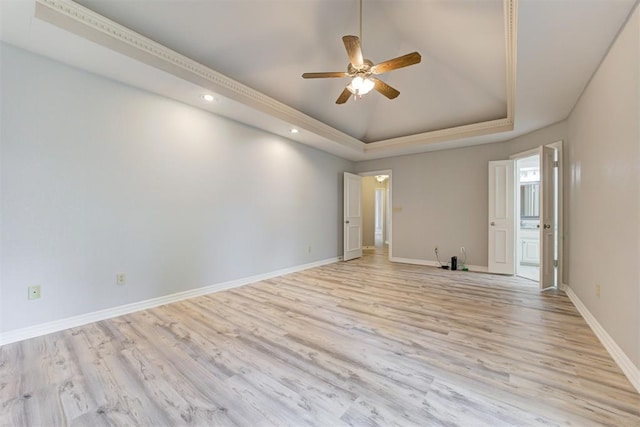 spare room with light wood-type flooring, a tray ceiling, and ceiling fan