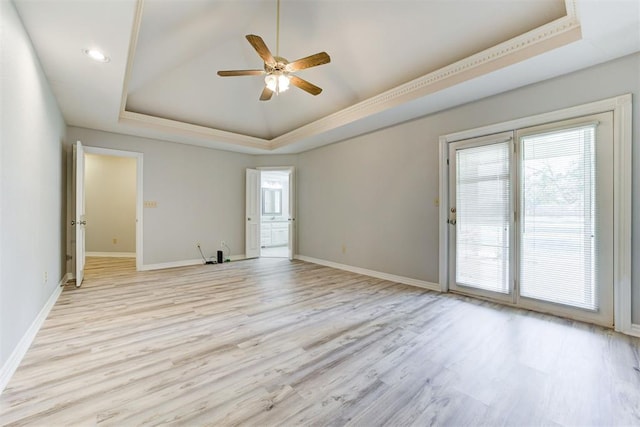 spare room with a tray ceiling, ceiling fan, and light hardwood / wood-style floors