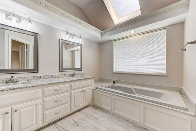 bathroom with vanity, vaulted ceiling with skylight, and a bathtub