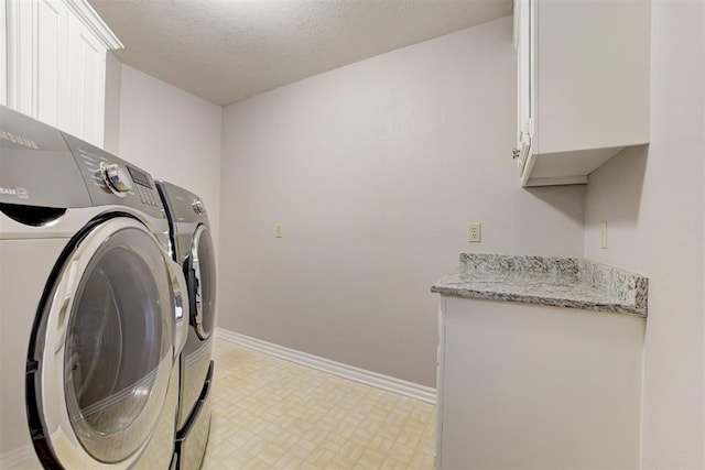 laundry room featuring washer and dryer, a textured ceiling, and cabinets