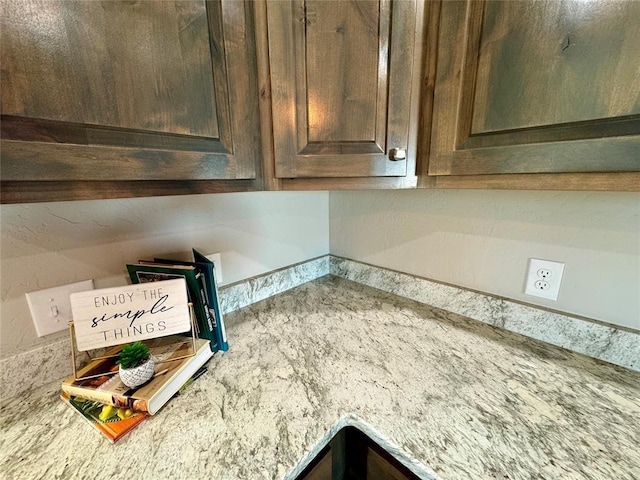 details featuring dark brown cabinetry and light stone counters