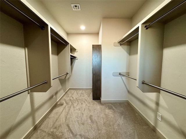 walk in closet with light colored carpet